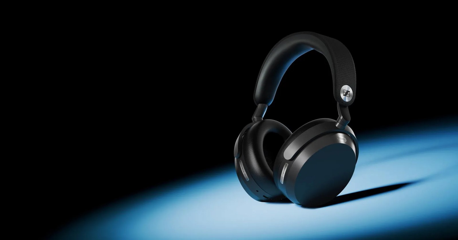 หูฟังครอบ Sennheiser MOMENTUM 5 Wireless สีดำ ตั้งอยู่ใต้แสงไฟสีฟ้าบนพื้นหลังมืด